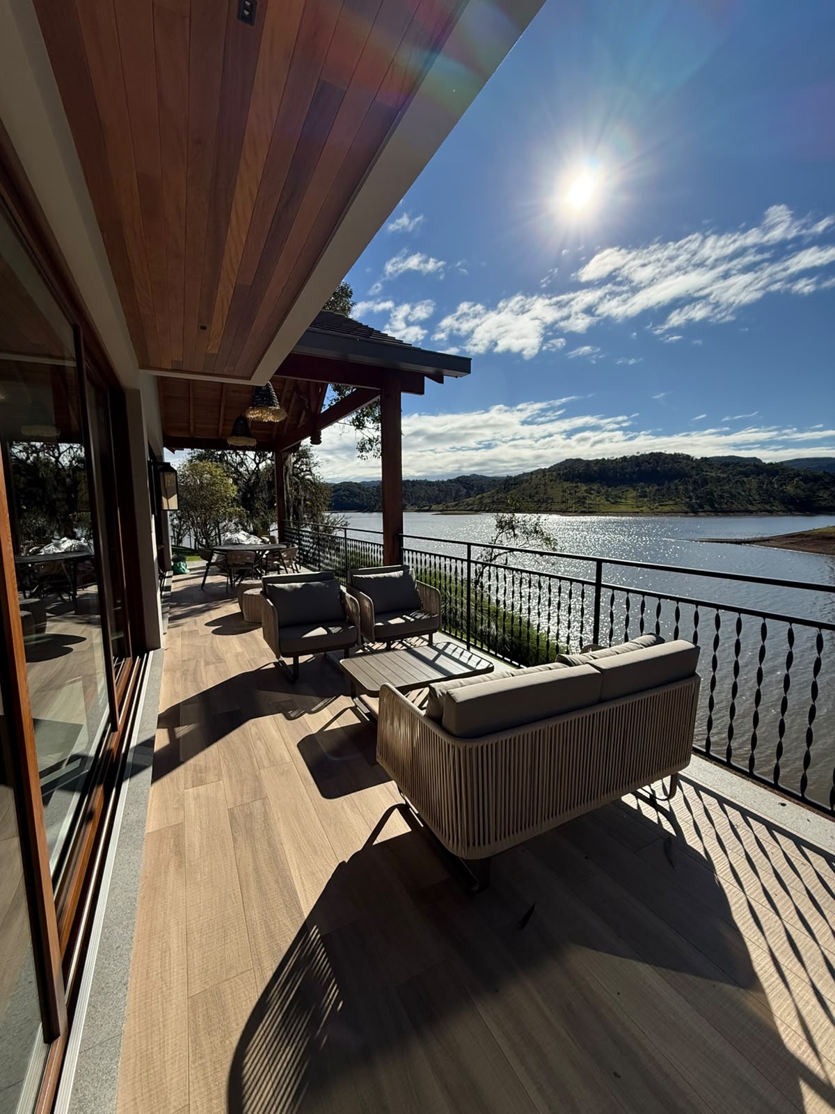 Terraza con sofá de cuerda de Mavie y almohadones de tejido impermeable, con vistas al lago